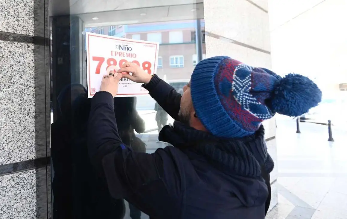 Un afortunado pega el cartel con el número agraciado en la fachada de El Corte Inglés. Foto: Campillo