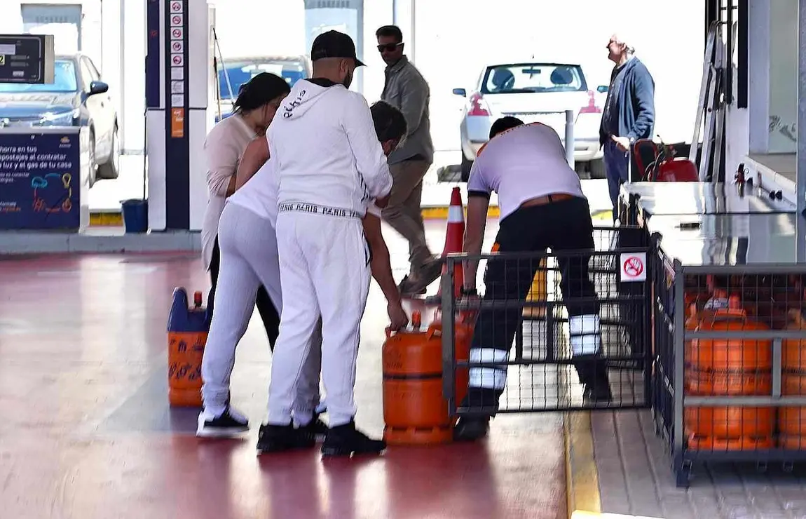 Un grupo de personas se apresura a coger bombonas de gas en una gasolinera.