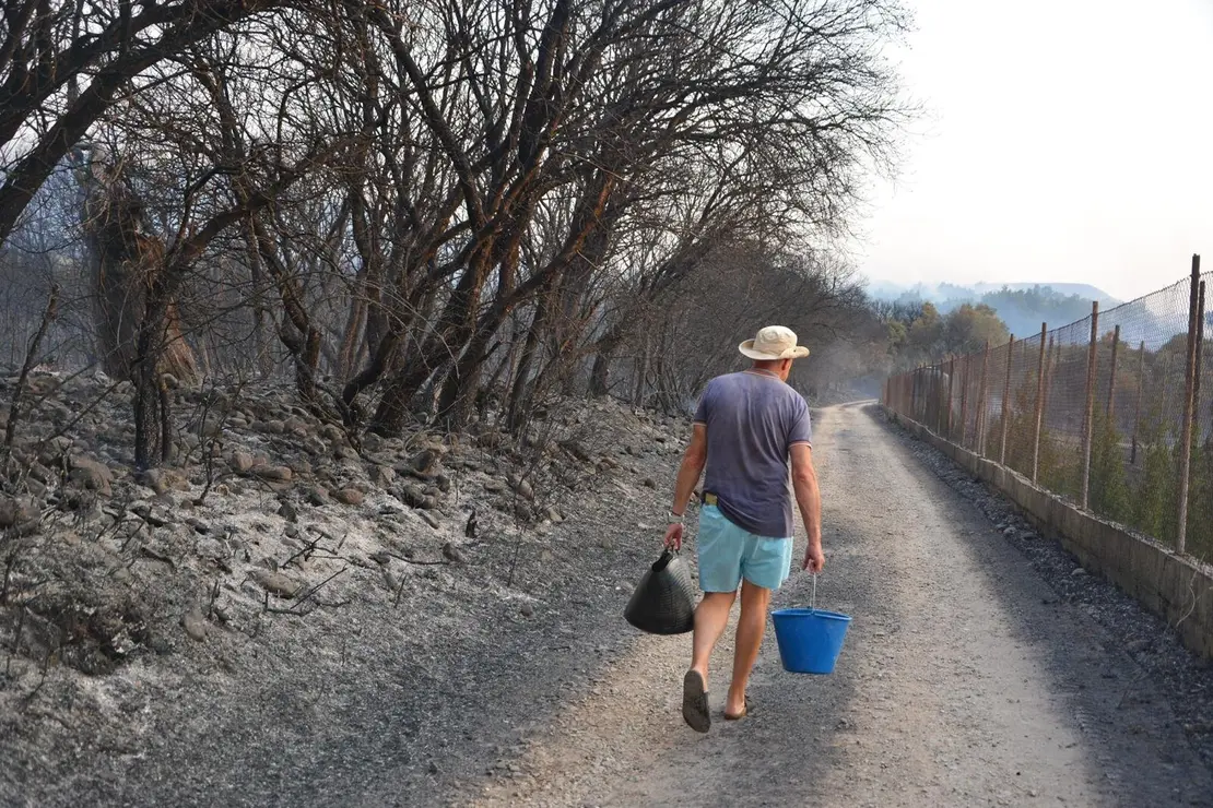 Un vecino intenta, con calderos de agua, sofocar los restos de las llamas. La imagen, publicada por El Bierzo Digital, ha sido realizada por Quinito.