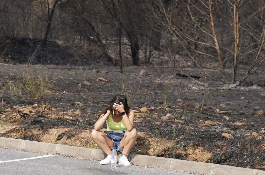 Una mujer se lamenta junto al terreno calcinado por las llamas. Foto: César HIjosa