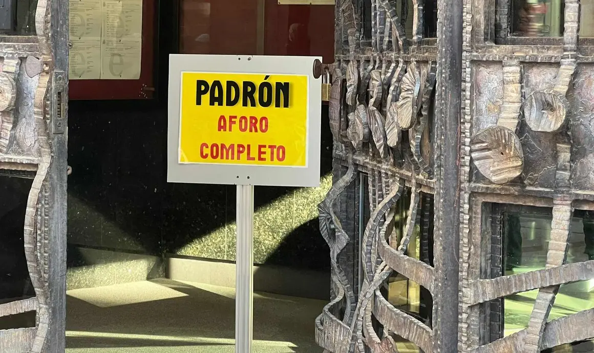 Un cartel 'fosforito' advierte de la imposibilidad de atender a nuevos migrantes que soliciten documentaci&oacute;n en el padr&oacute;n municipal. El proceso de regularizaci&oacute;n ha provocado una masiva presencia de demandantes de documentaci&oacute;n, visible desde antes de que se abran las dependencias municipales. Fotos: Luc&iacute;a Ramajo