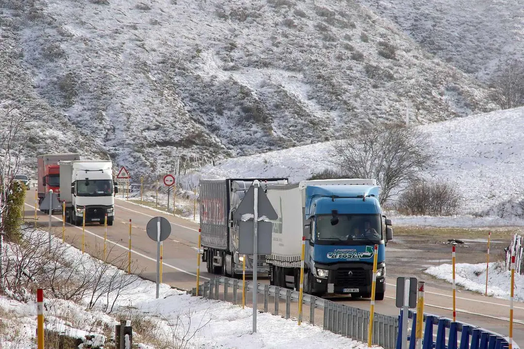 Vehículos pesados en el Puerto de Pajares, con nieve en las laderas. Foto: Peio García