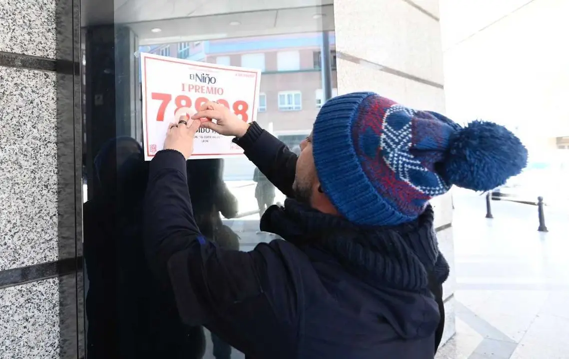 Un afortunado pega el cartel con el número agraciado en la fachada de El Corte Inglés. Foto: Campillo