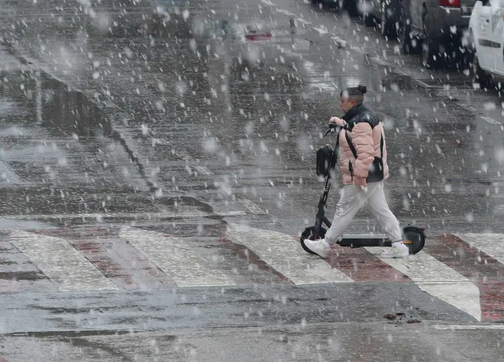 Un joven circula con su patinete bajo la nieve. Foto: César Sánchez