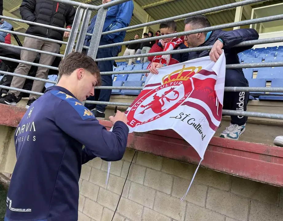 Un jugador de la Cultural firma la bandera del club a un aficionado en un entrenamiento.