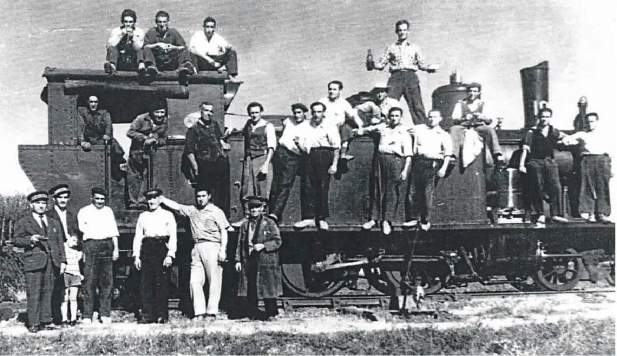 Un grupo de trabajadores junto a una de las locomotoras del 'tren burra'.