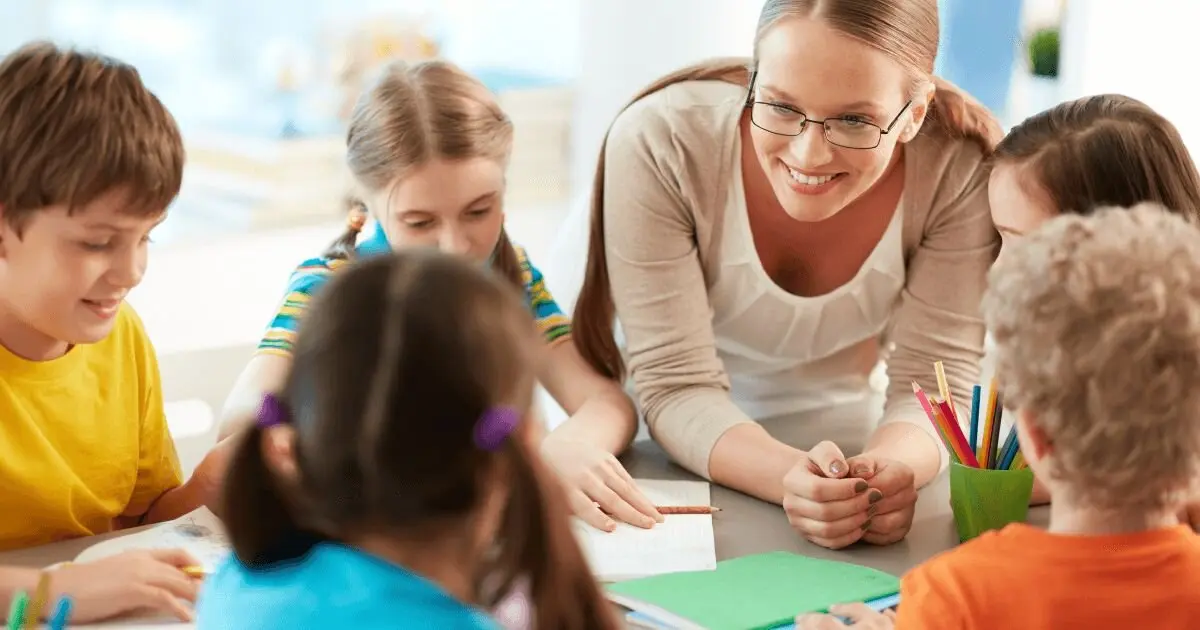 Un grupo de niños junto a una profesora en un aula.