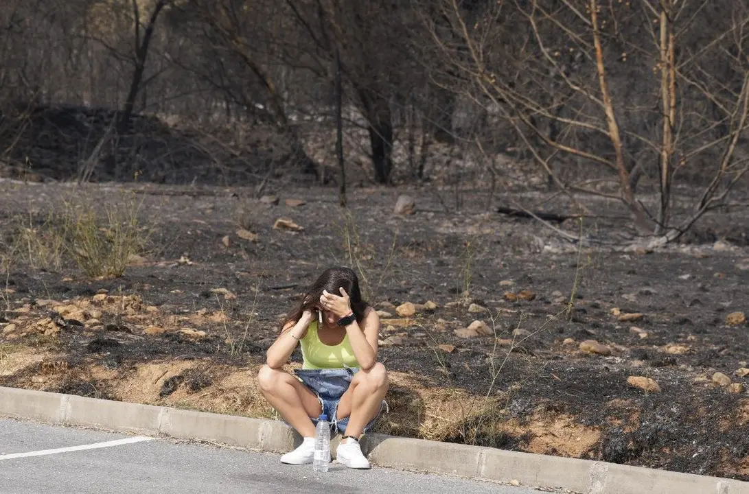 Una mujer se lamenta junto al terreno calcinado por las llamas. Foto: César HIjosa