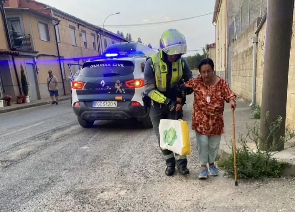 Un agente de la Guardia Civil ayuda a una señora a ser evacuada por el incendio. Foto: Guarda Civil