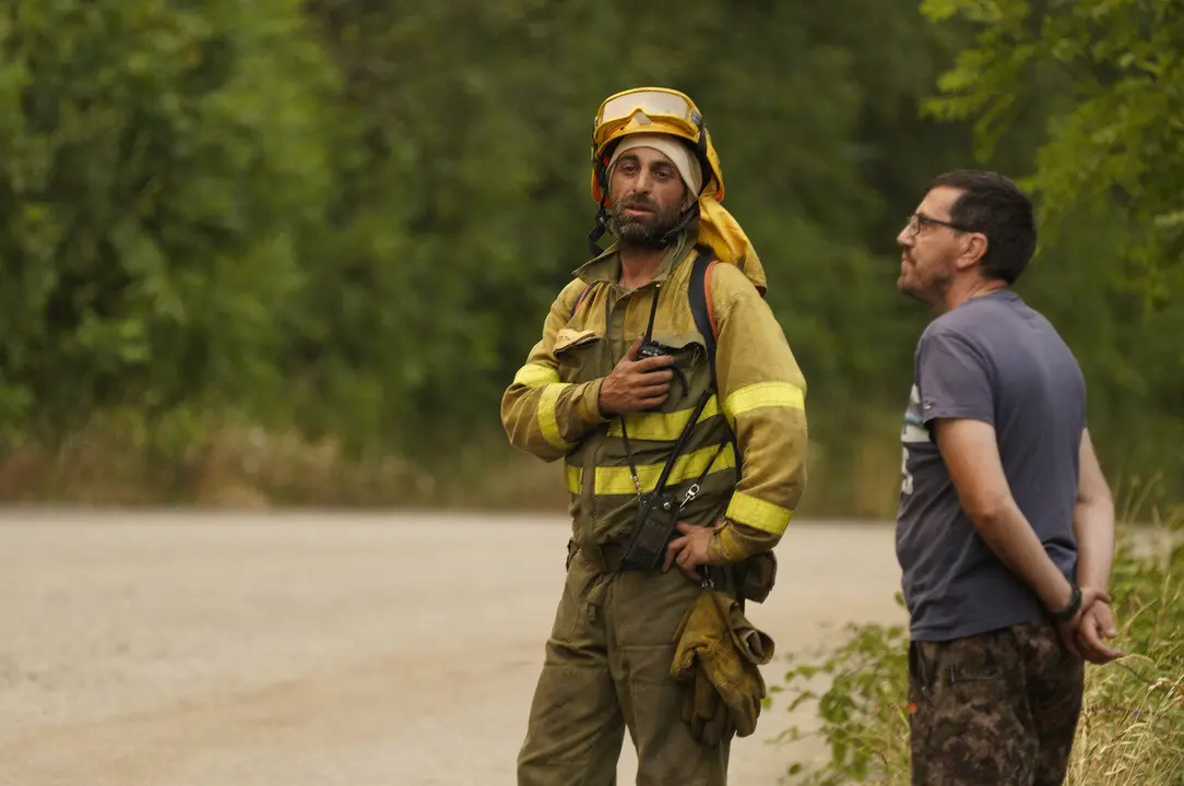 Un brigadista junto a un vecino durante un incendio en una imagen de archivo. Foto: C&eacute;sar