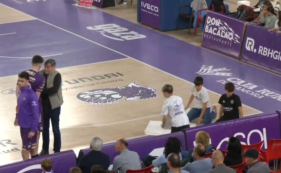 Tres jóvenes tratan de secar la pista del Pabellón Pisuerga