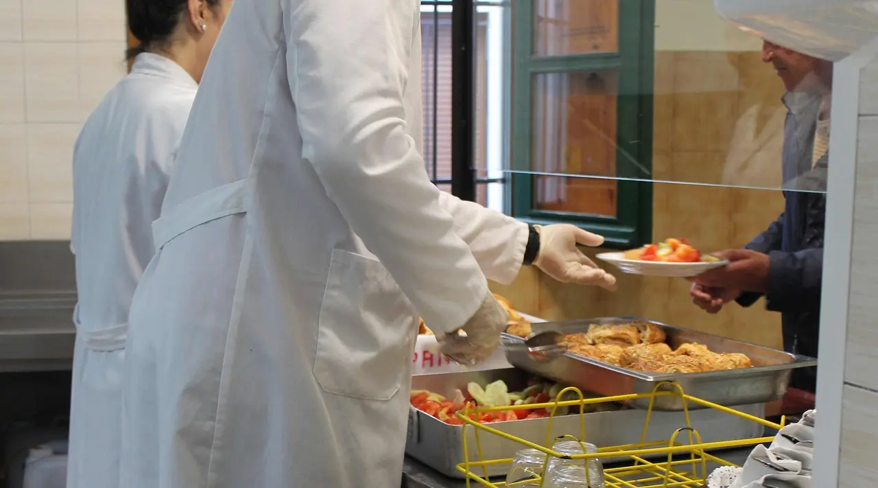 Voluntarias del comedor social sirven los men&uacute;s en la sala a la que acuden las personas sin hogar de la ciudad.