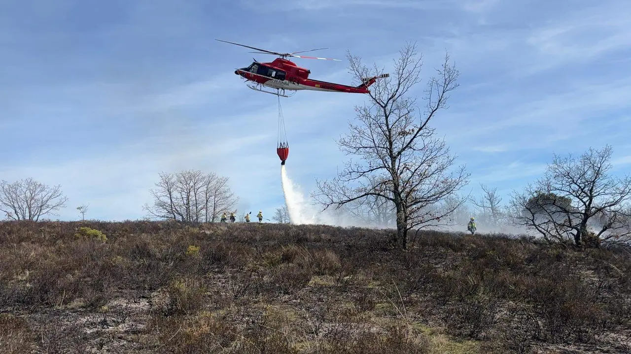 Un helic&oacute;ptero descarga agua este lunes en la zona del incendio.