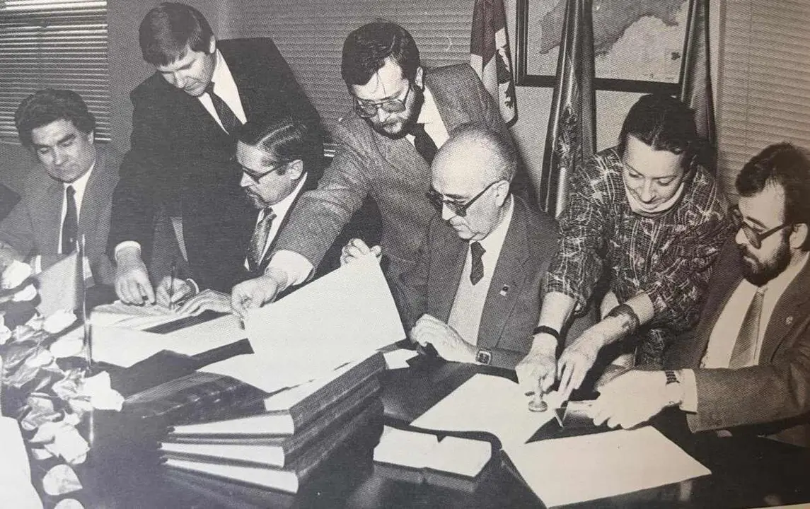 manuel_garcia_alvarez_en_el_centro_de_pie_sujetando_una_hoja_durante_una_firma_de_un_convenio_en_la_universidad