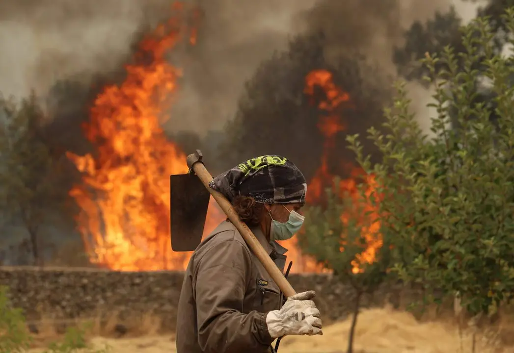 Un agricultor trata de defender su campo de un incendio forestal.