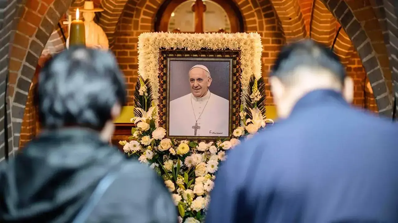 Un grupo de fieles reza ante la imagen del Papa Francisco.