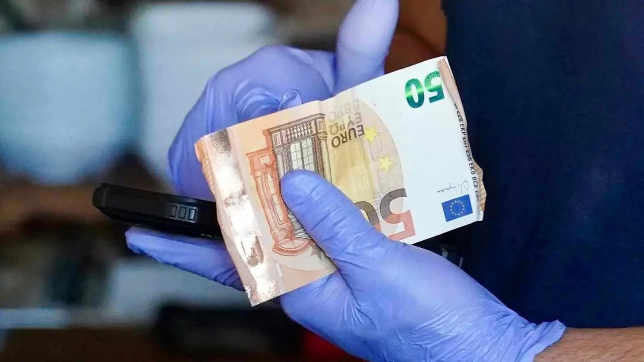 Un camarero recoge dinero en efectivo ante la imposibilidad de cobrar con tarjeta durante el apagón.