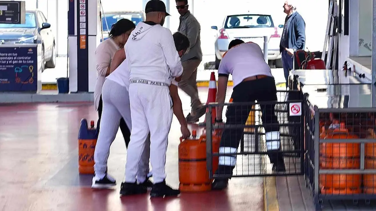 Un grupo de personas se apresura a coger bombonas de gas en una gasolinera.