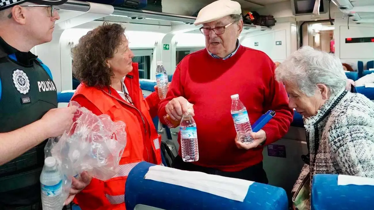 Cruz Roja y policía reparten agua y atienden a los pasajeros procedentes de Burgos estacionados en Valladolid.