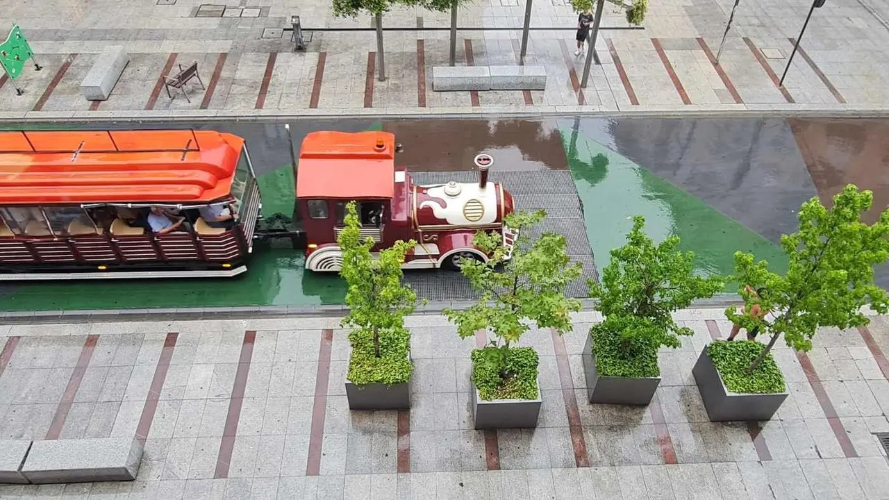 El tren turístico de la capital avanza por Ordoño II en la tarde de este martes bajo la lluvia.