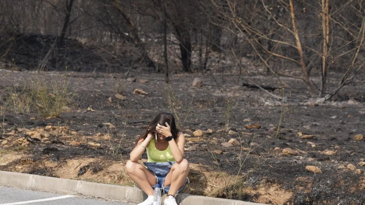 Una mujer se lamenta junto al terreno calcinado por las llamas. Foto: César HIjosa