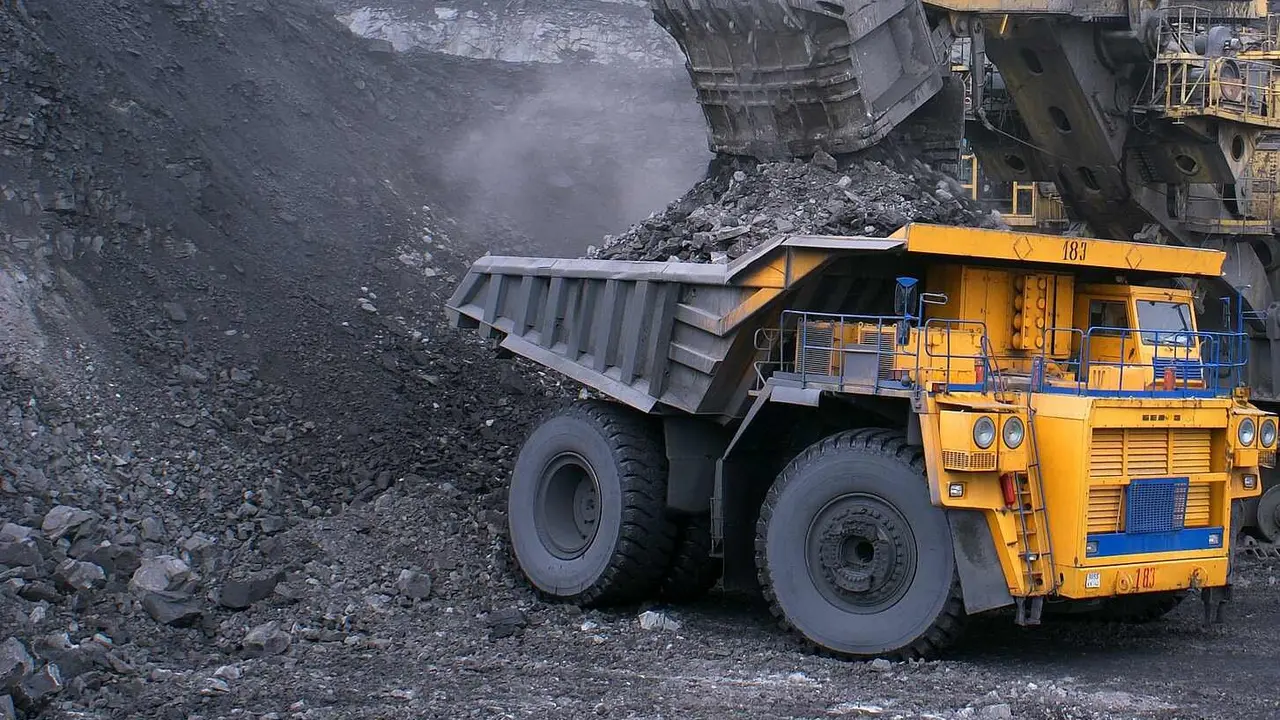 Maquinaria pesada retirando mineral de una montaña de carbón.