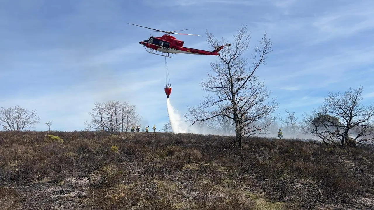 Un helic&oacute;ptero descarga agua este lunes en la zona del incendio.