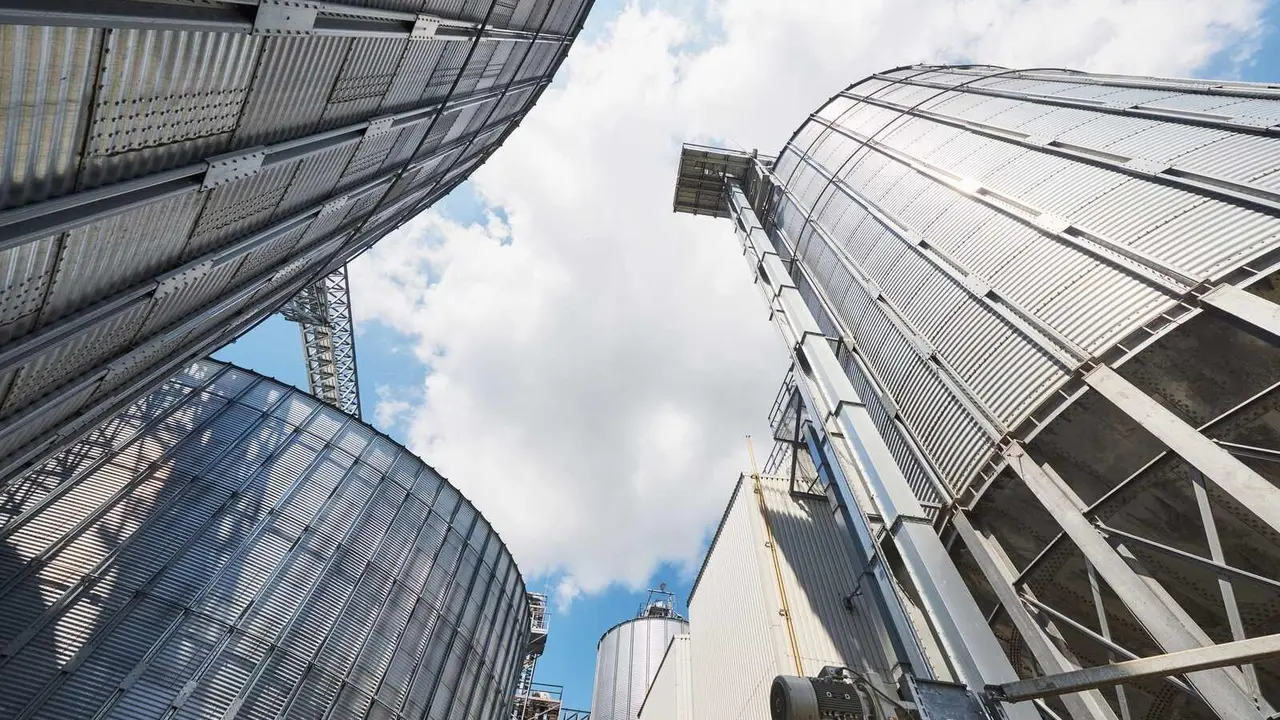 Agricultural Silos. Building Exterior. Storage and drying of grains, wheat, corn, soy, sunflower against the blue sky with white clouds.
