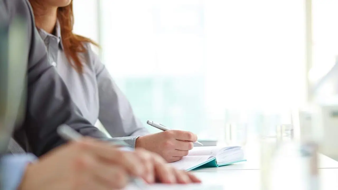 Hand of businesswoman with ballpoint over open notebook at convention
