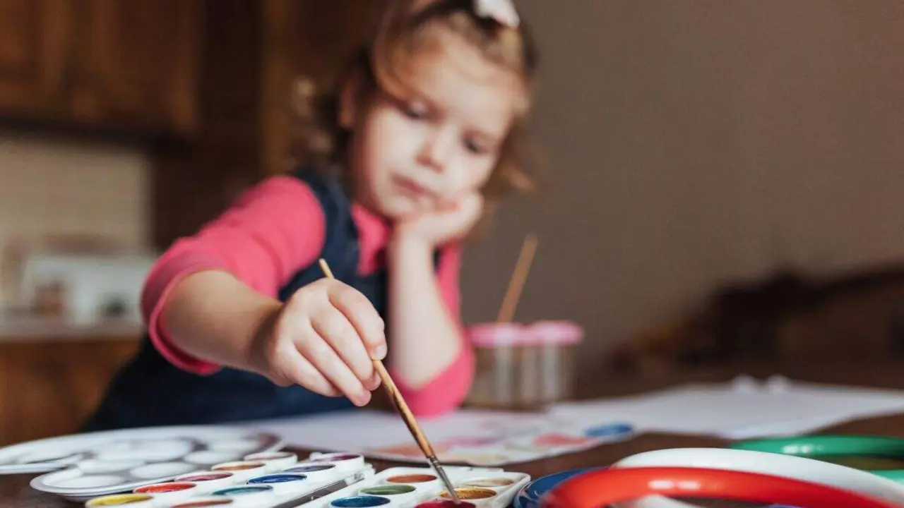 Cute happy little girl, adorable preschooler, painting with water color on canvas. Baby close up.