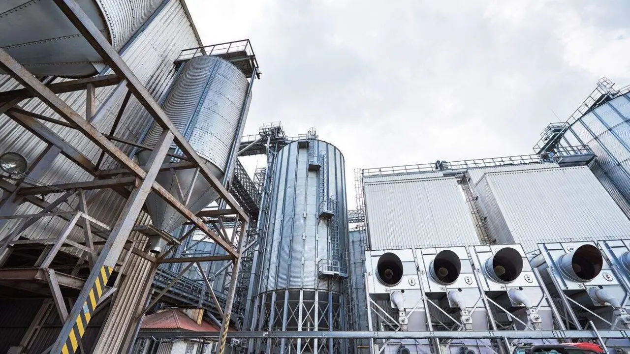 Agricultural Silos. Building Exterior. Storage and drying of grains, wheat, corn, soy, sunflower against the blue sky with white clouds.