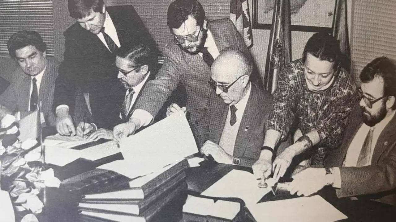 manuel_garcia_alvarez_en_el_centro_de_pie_sujetando_una_hoja_durante_una_firma_de_un_convenio_en_la_universidad
