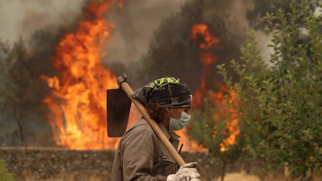 Un agricultor trata de defender su campo de un incendio forestal.