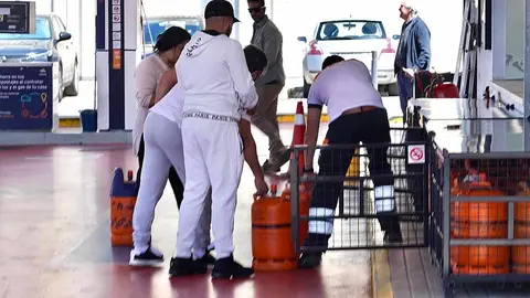 Un grupo de personas se apresura a coger bombonas de gas en una gasolinera.