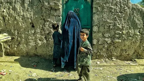 Una madre afgana vestida con el tradicional burka a la puerta de su casa junto a dos de sus hijos. Foto: A. F. Reca