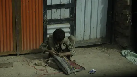 Un niño afgano cose una alfombra en las calles de Kabul. Foto: A. F. Reca
