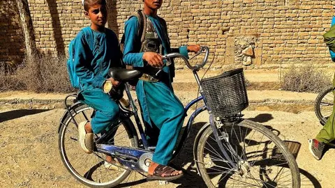 Dos niños afganos comparten bicicleta para acudir a la escuela. Foto: A. F. Reca