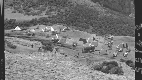Escenas agrícolas entre Riaño y Portilla de la Reina [Valle con tiendas de campaña y carros de madera para tareas de labranza en el Parque nacional de Picos de Europa]