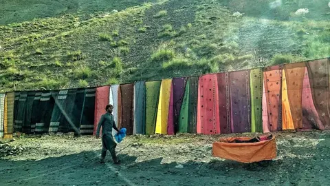 Un hombre vende telas de colores junto a la carretera de Kabul a Sorobi, en Afganistán. Foto: Alfonso F. Reca