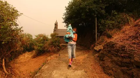 Una vecina de Lusio (León), rescata la Santa del pueblo ante la posible llegada del fuego. Fotos: César Hornija