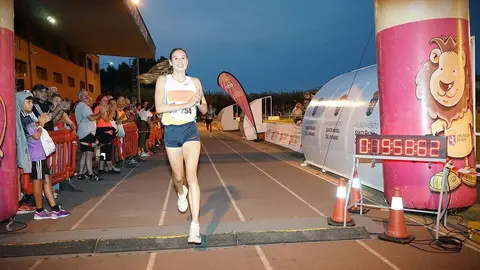 Imagen de la ganadora de la carrera de la Legua Nocturna de Santa María del Páramo cruzando la línea de meta.