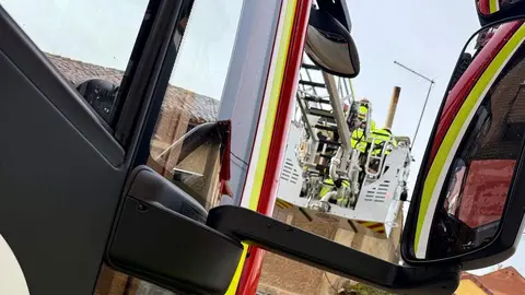 Efectivos de Bomberos de León retirando tejas de una vivienda en mal estado de conservación en Puente Castro.
