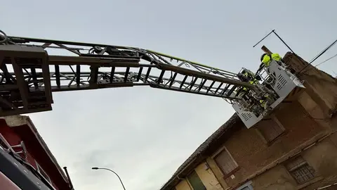 Efectivos de Bomberos de León retirando tejas de una vivienda en mal estado de conservación en Puente Castro.