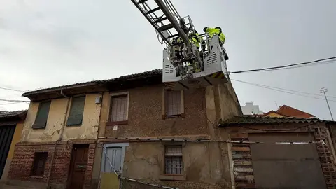 Efectivos de Bomberos de León retirando tejas de una vivienda en mal estado de conservación en Puente Castro.