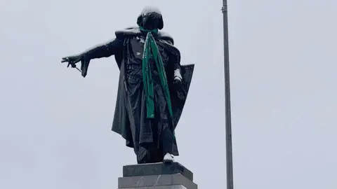 La estatua de Guzmán, en León capital, ha aparecido este miércoles con una bufanda verde recordando que en esta jornada se conmemora el Día Mundial contra el Cáncer. Fotos: Silvia García