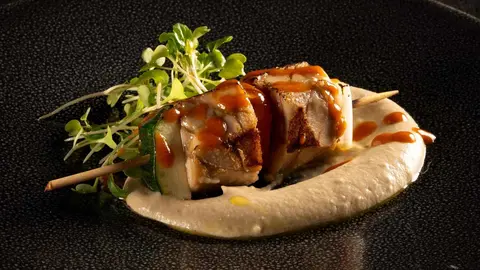 Pincho a la parrilla de mollejas con verduras y salsa barbacoa.