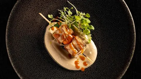 Pincho a la parrilla de mollejas con verduras y salsa barbacoa.