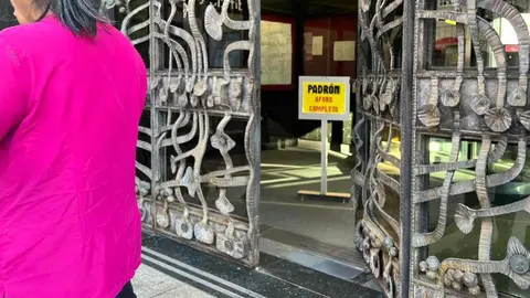 Un cartel 'fosforito' advierte de la imposibilidad de atender a nuevos migrantes que soliciten documentación en el padrón municipal. El proceso de regularización ha provocado una masiva presencia de demandantes de documentación, visible desde antes de que se abran las dependencias municipales. Fotos: Lucía Ramajo