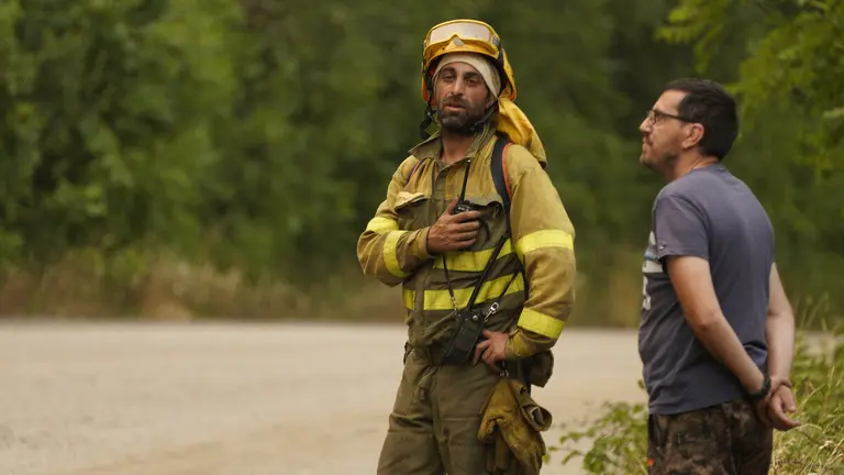 Un brigadista junto a un vecino durante un incendio en una imagen de archivo. Foto: C&eacute;sar